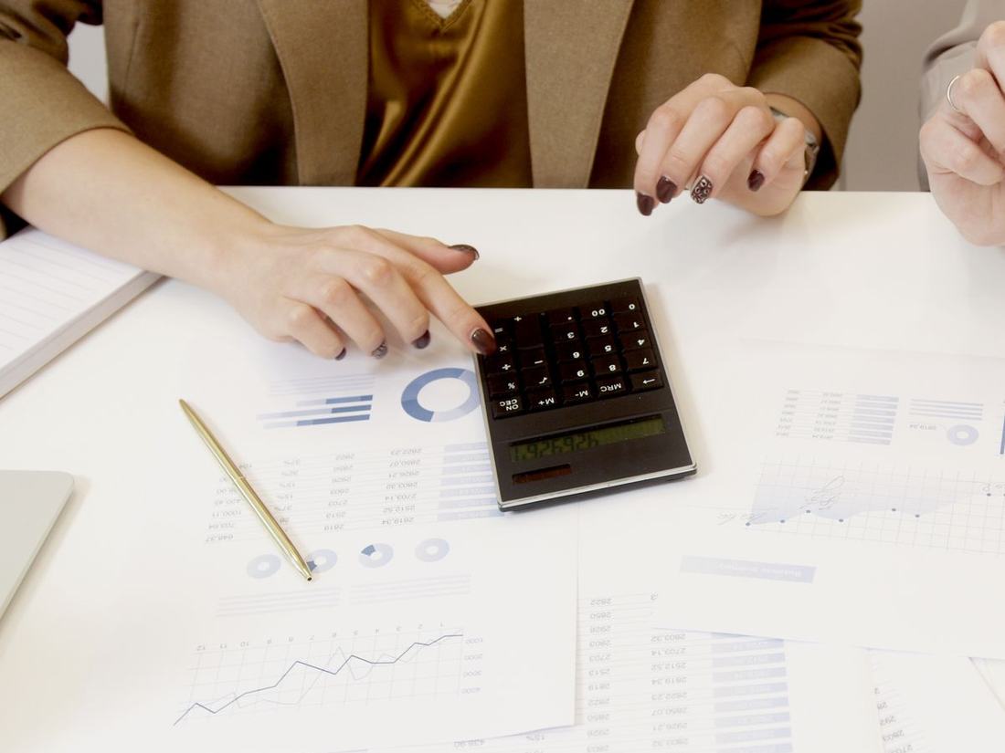 Mesa com relatórios, gráficos impressos e uma calculadora durante uma análise financeira